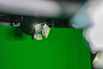 un projecteur fresnel silencieux derrière un fond vert éclaire un contre-jour en studio acoustique